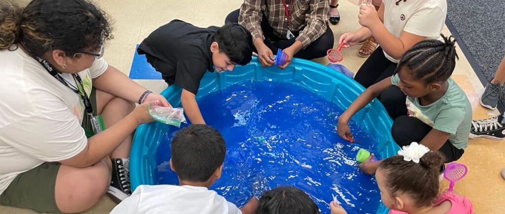 Student play in a small pool of water
